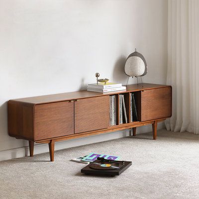 a record player is sitting on the floor next to a book shelf with cds in it