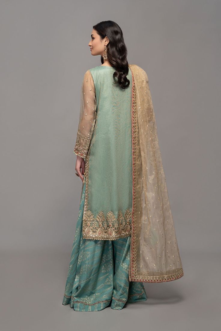 Sharara Style Salwar Kameez Pakistani Eid Dress is an exquisitely designed Zari net fully embroidered shirt with embroidered sleeves Jacquard sharara which can be customized according to your choice. It is paired with a zari net embroidered dupatta. Detailed Description: SKU: PN800 Detailing: Gota, sheesha, dabka, sequins Color: Ferozi Fabric: Raw Silk, Net, Organza Design: Fully embellished, Embroidery, Dabka Event: Eid Party, Wedding, Festive, Party wear Designer Long Sleeve Sharara For Eid, Long Sleeve Raw Silk Lehenga With Dabka, Eid Sharara With Sheer Dupatta, Eid Sharara With Intricate Embroidery In Tissue Silk, Eid Sharara With Intricate Embroidery On Tissue Silk, Eid Tissue Silk Sharara With Intricate Embroidery, Eid Long Sleeve Sharara With Sheer Dupatta, Embroidered Organza Sharara With Straight Kurta, Designer Semi-stitched Jamawar Sharara