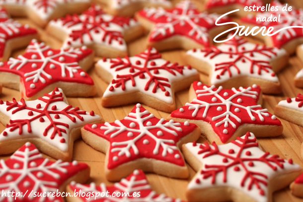 decorated cookies are arranged on a wooden table with white and red frosted snowflakes