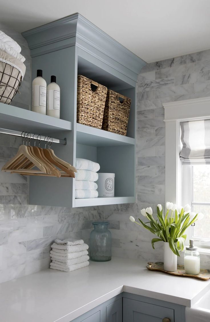 a white counter top in a kitchen next to a shelf filled with towels and other items