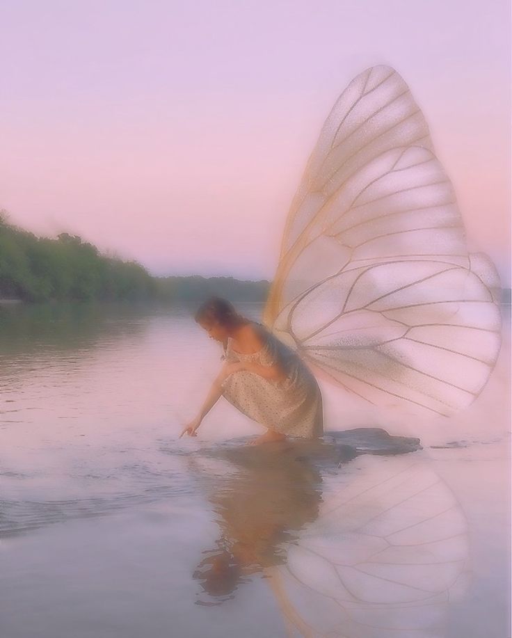 a woman kneeling down in the water with a butterfly wing on her back and body