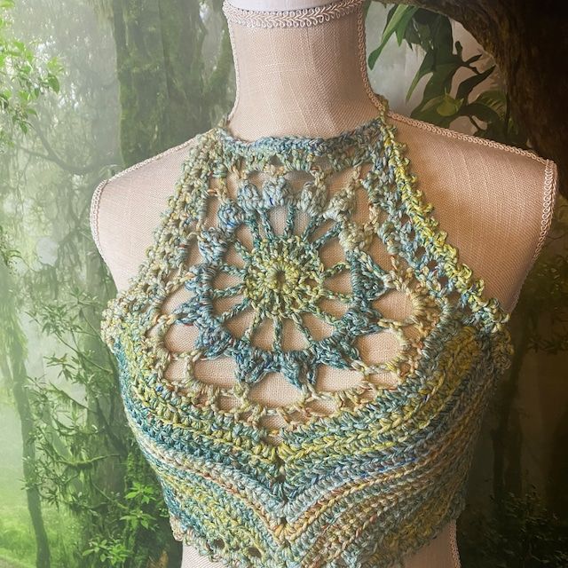 a crocheted top on a mannequin with trees in the background