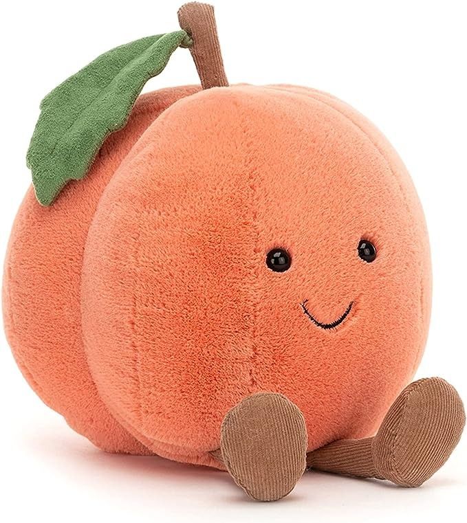 an orange stuffed animal with a green leaf on it's head, sitting against a white background