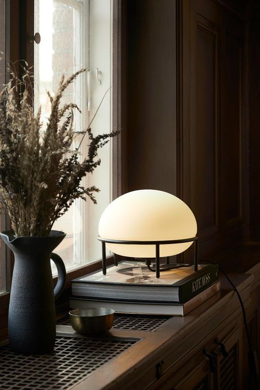 a table lamp sitting on top of a book next to a vase