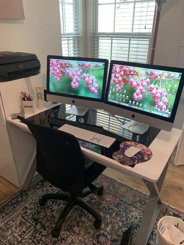 two computer monitors sitting on top of a desk next to each other in front of a window