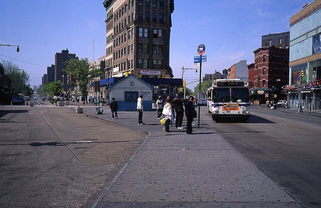 people are standing on the sidewalk in front of a bus