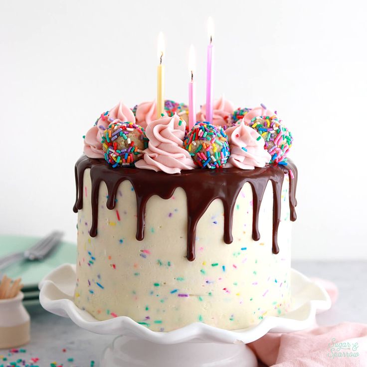 a birthday cake with chocolate icing and sprinkles on a white plate