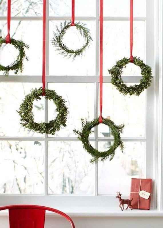 christmas wreaths hanging on the window sill in front of a red chair and presents