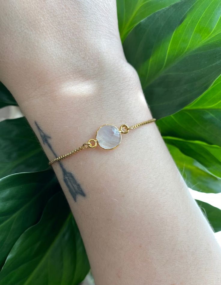 This minimalist style moonstone bracelet is perfect for everyday wear. It's beautiful on its own, but also makes a great layering piece. Created with a gold electroplated rainbow moonstone connector that is attached to a dainty gold plated chain with a slider bead that makes it adjustable. It is finished off with two gold ball ends. #gemstonejewelry #moonstone #minimalist Minimalist Gold Chain Bracelet With Gemstone, Everyday Round Moonstone Bracelets, Minimalist Gold Crystal Bracelet For Everyday, Everyday Moonstone Bracelets, Minimalist Gold Crystal Bracelet, Dainty Moonstone Bracelets For Everyday, Gold Moonstone Round Bracelets, Spiritual Gold Bracelets With Moonstone, Gold Minimalist Crystal Bracelet