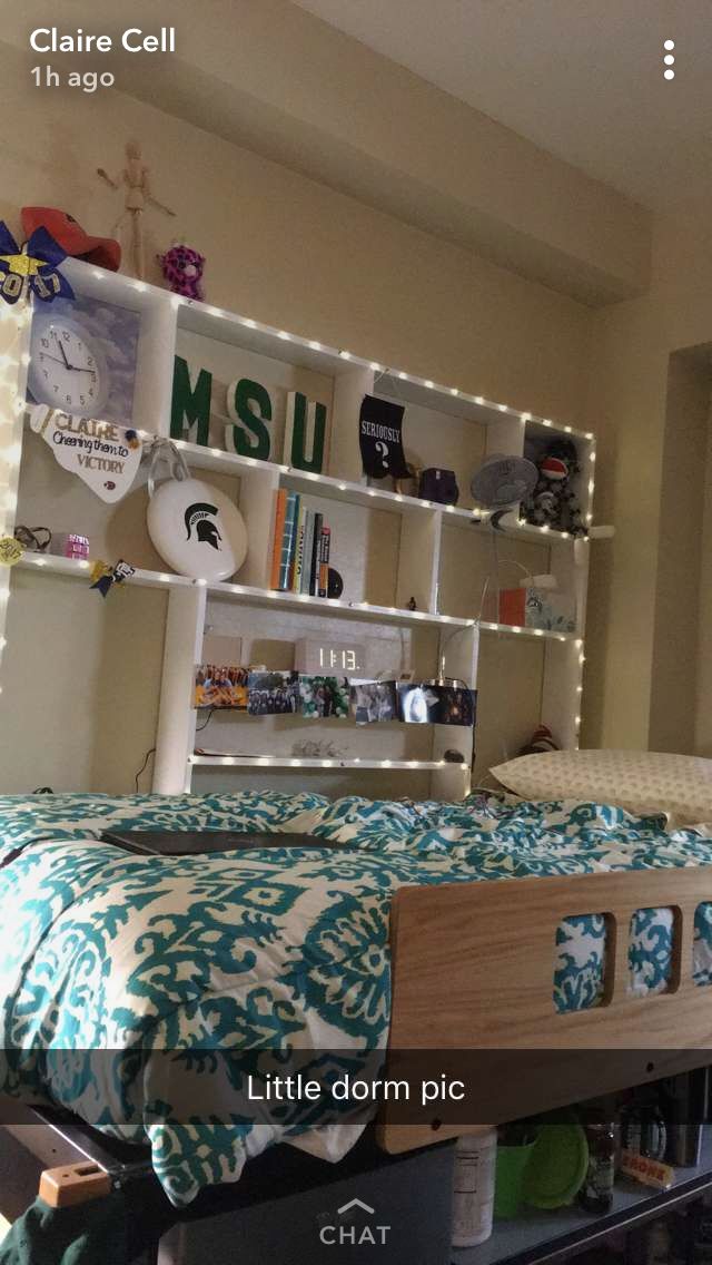 a bedroom with a bed, bookshelf and other items on the shelf above it