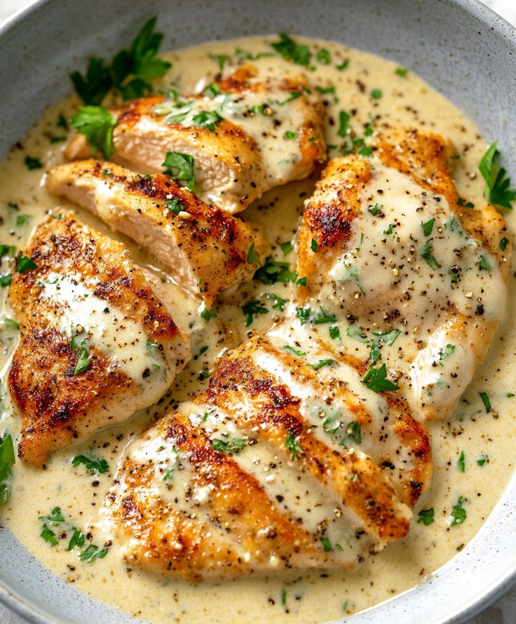 some chicken in a white sauce with parsley on top