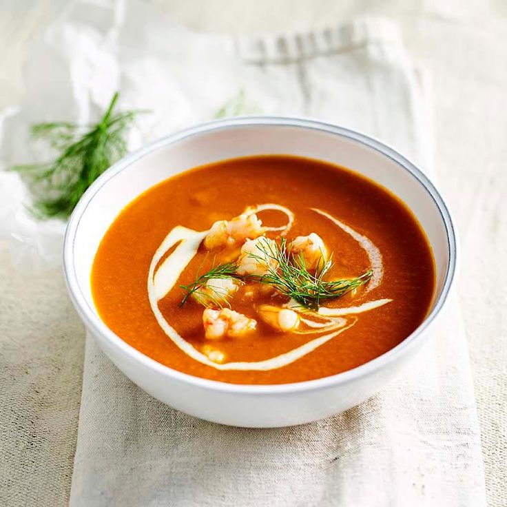 a white bowl filled with tomato soup and garnish