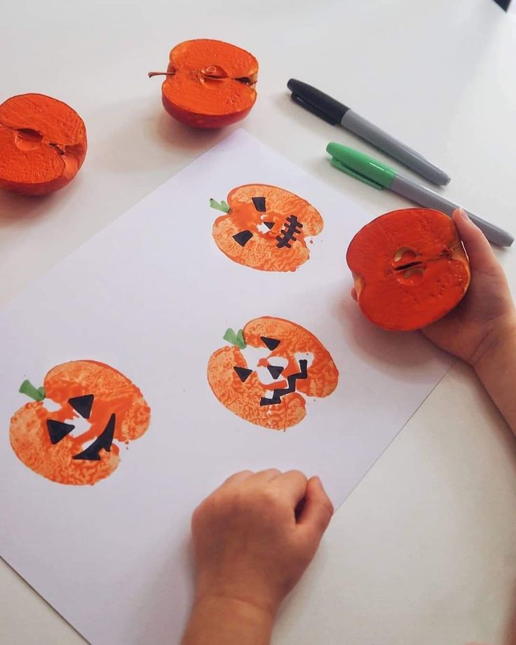 a child is making pumpkin faces out of toilet paper with crayons on the table