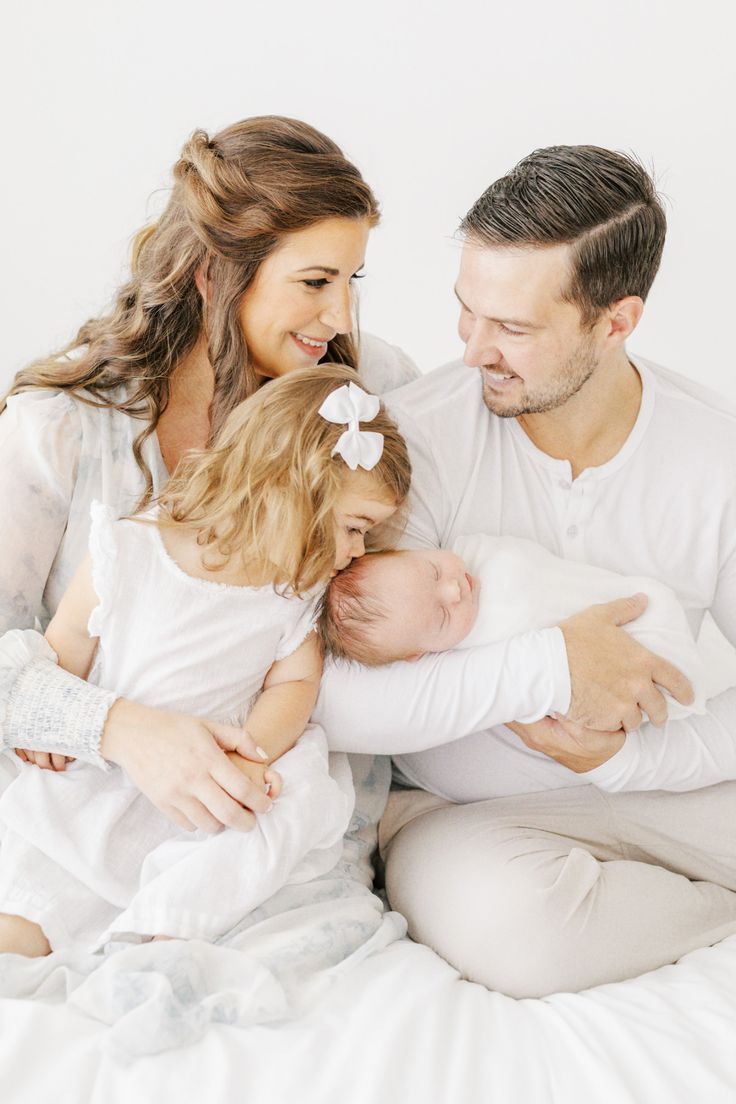 a man, woman and child are sitting on a bed with their arms around each other