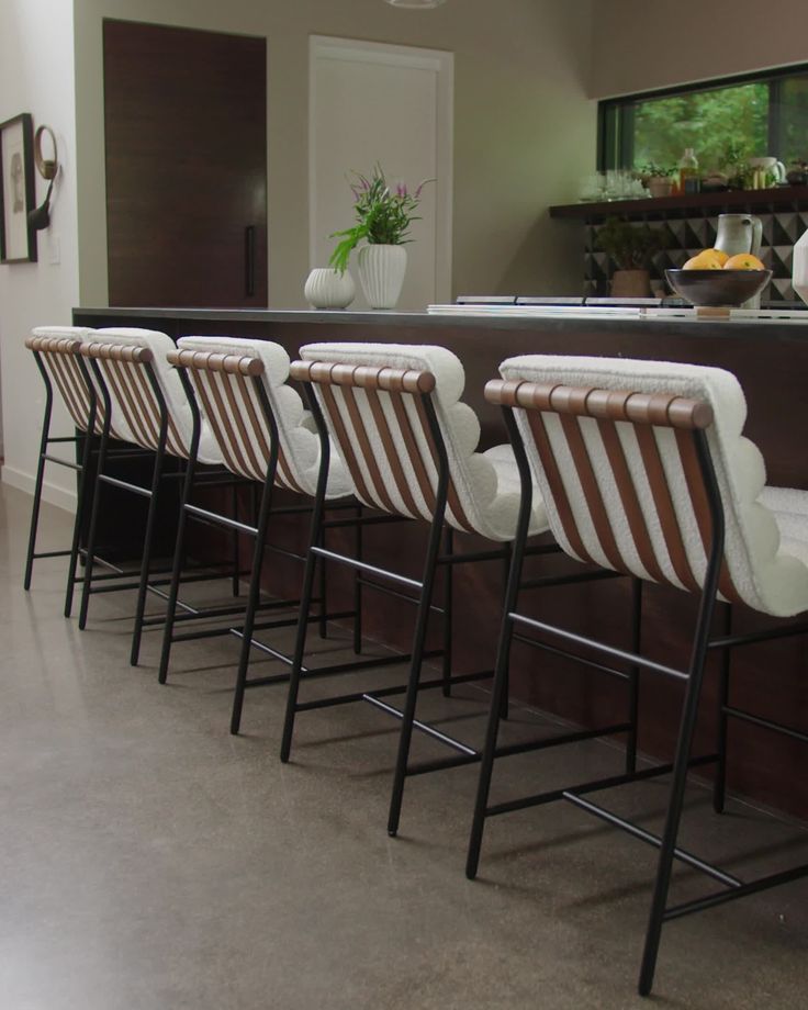 a row of chairs sitting next to each other in front of a bar