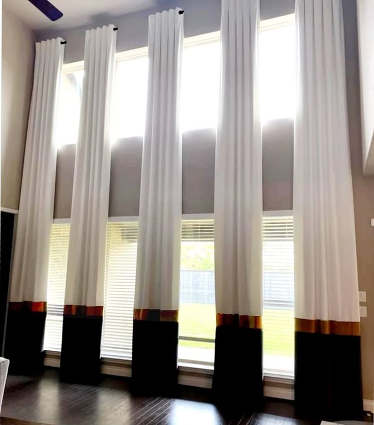 the curtains are hanging in front of the windows with white drapes and brown trim