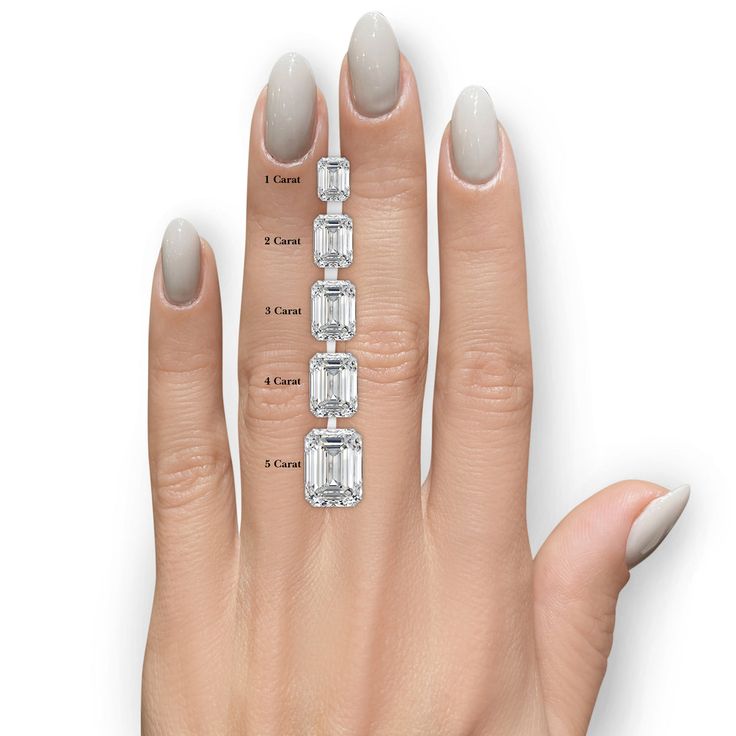 a woman's hand with three different sized diamonds on the middle finger and four smaller emerald