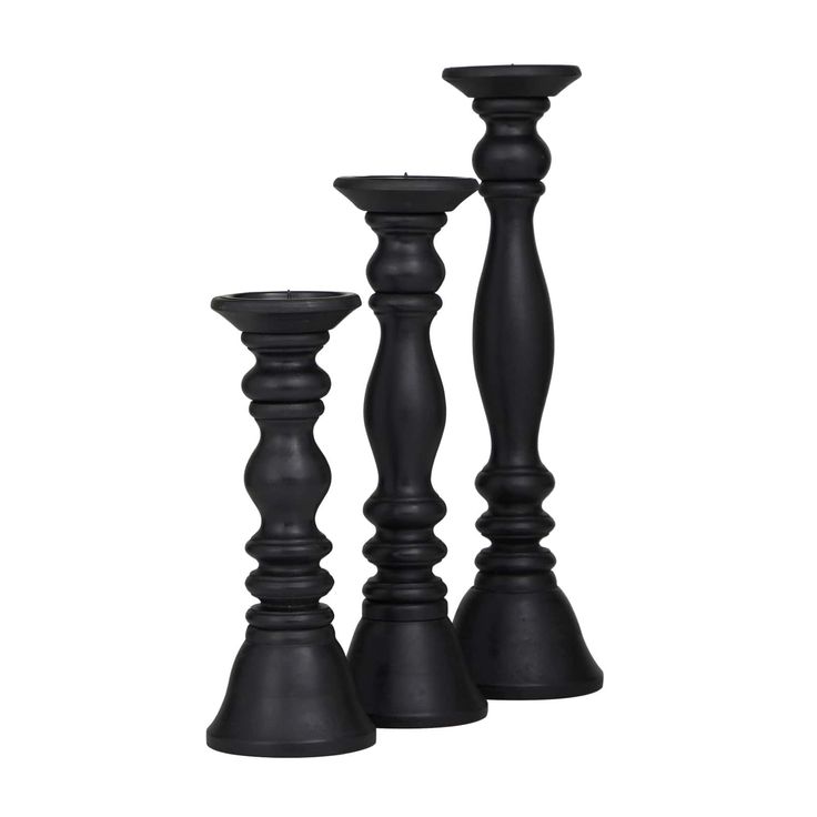 three black candlesticks sitting next to each other