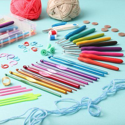 there are many crochet hooks and knitting needles on the blue table with balls of yarn