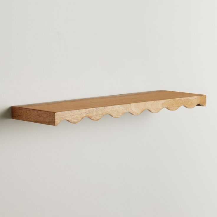 a wooden shelf mounted to the wall with scalloped wood trim on it's sides