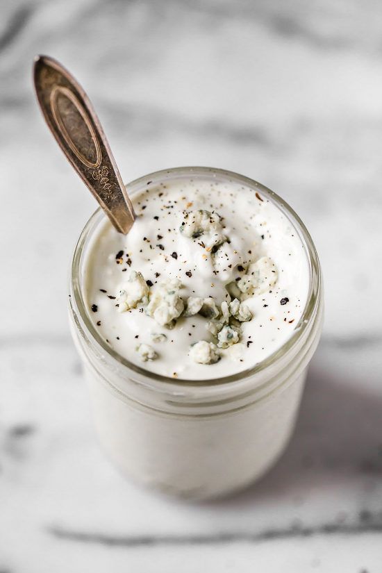 a glass jar filled with whipped cream on top of a white counter next to a wooden spoon