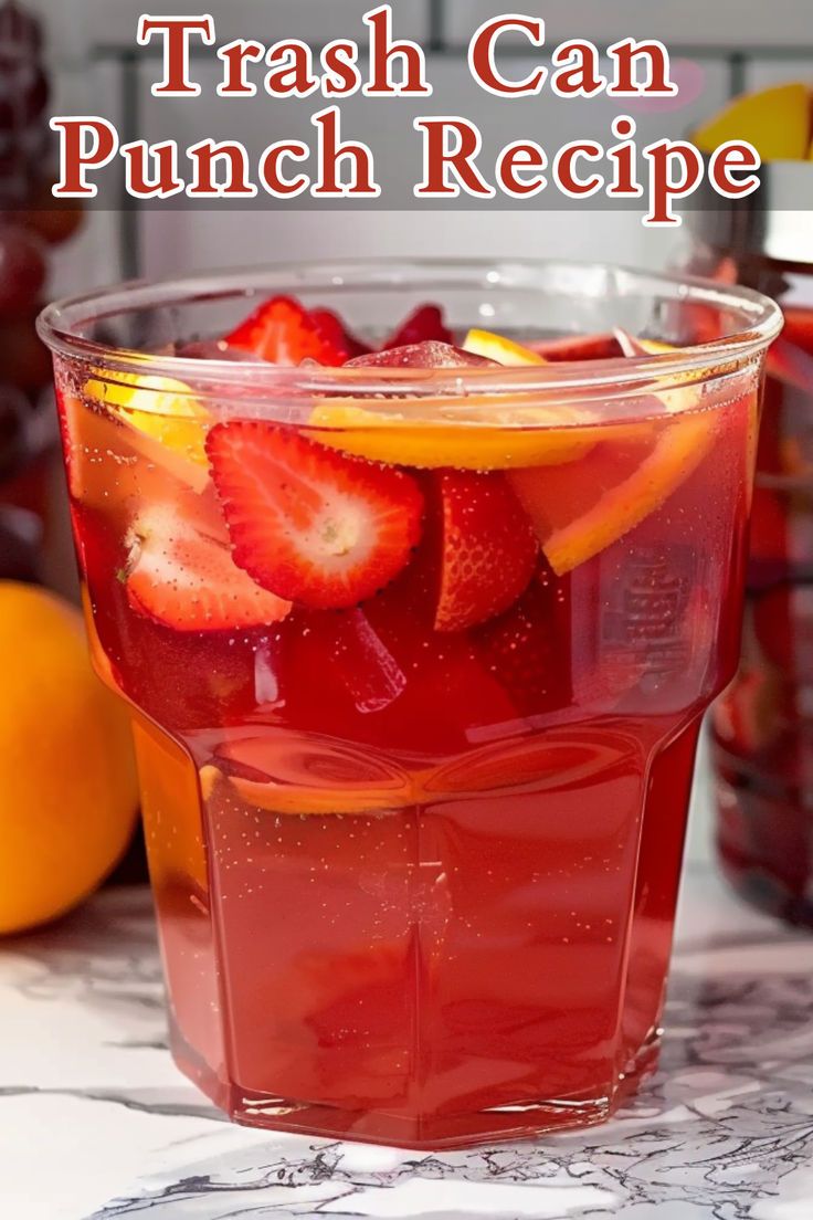 a glass filled with liquid and strawberries on top of a table next to lemons