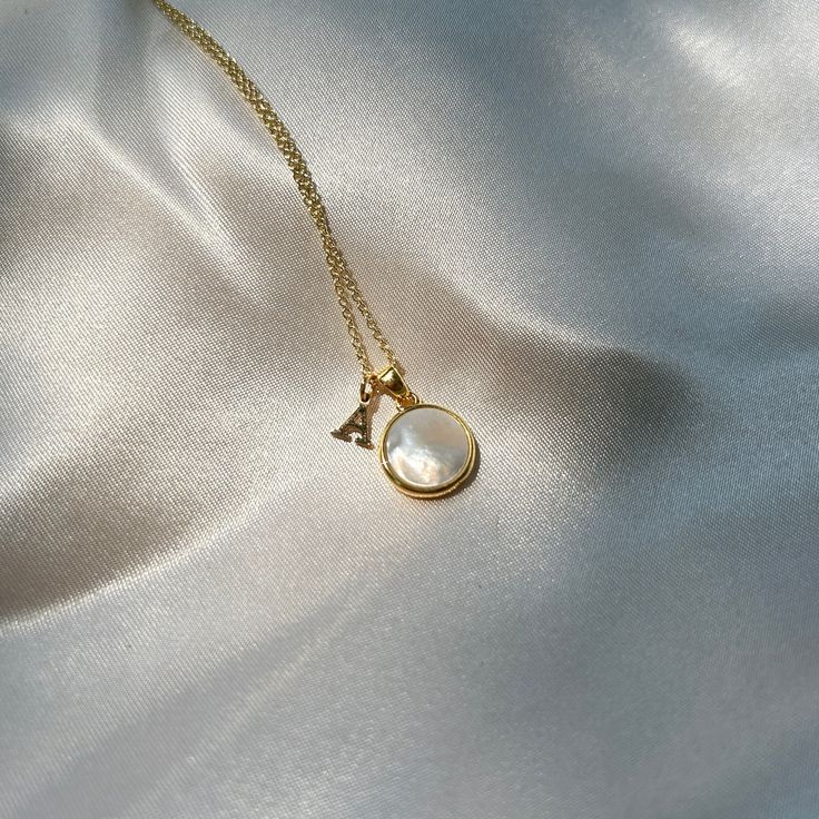 A minimalist gold mother of pearl circular pendant. Mother-of-pearl shell is commonly believed to attract prosperity and is often used in mystical work and lore to heighten intuition, sensitivity and imagination - making this a beautiful gift for a loved one. When sunlight touches the mother of pearl pendant, it reflects brilliantly, causing it to glow on the wearer's neck. You can see partial reflections in it, a little like a mirror. Each pendant can be personalized with the first letter of a name, adding a personalized touch that makes it a cherished keepsake. The smooth, iridescent surface of the mother of pearl reflects light beautifully, creating a subtle and enchanting glow around the wearer's neckline. 🌼 Personalization: -You can choose to personalize this necklace by adding a let Elegant Gold Plated Birth Flower Necklace, Elegant Charm Necklace With Birth Flower And Initial Pendant, Gold Charm Necklace With Pearl Pendant For Anniversary, Adjustable Gold Necklace With Birth Flower, Elegant Round Birth Flower Charm Necklaces, Elegant Birth Flower Pendant Charm Necklace, Elegant Birth Flower Charm Necklace, Gold Elegant Charm Necklace With Initials, Elegant Gold Charm Necklaces With Initials