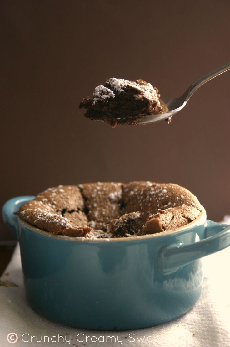 a spoon with some food in it on top of a blue bowl and white cloth