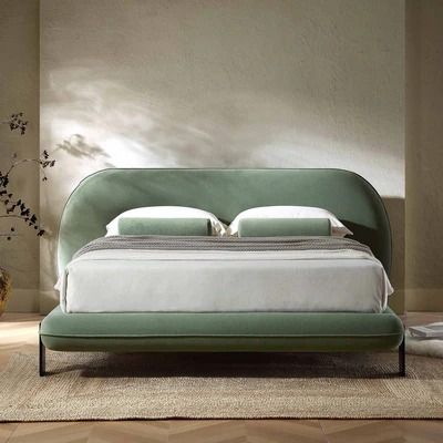 a bedroom with a green bed frame and white linens on the headboard, along with an area rug