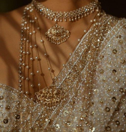 the back of a woman's dress with pearls and jewelry on her neckline