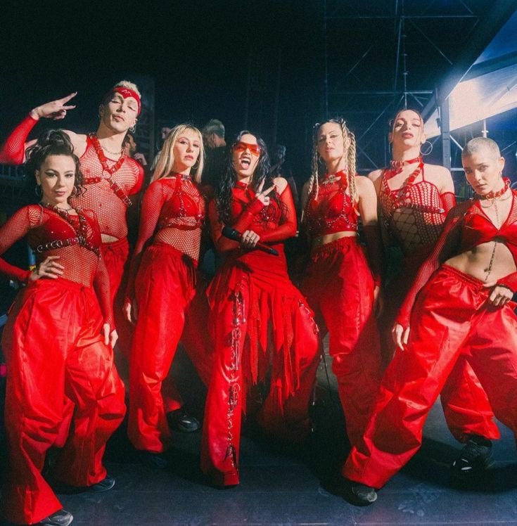 a group of people in red outfits posing for a photo on stage with their arms around each other