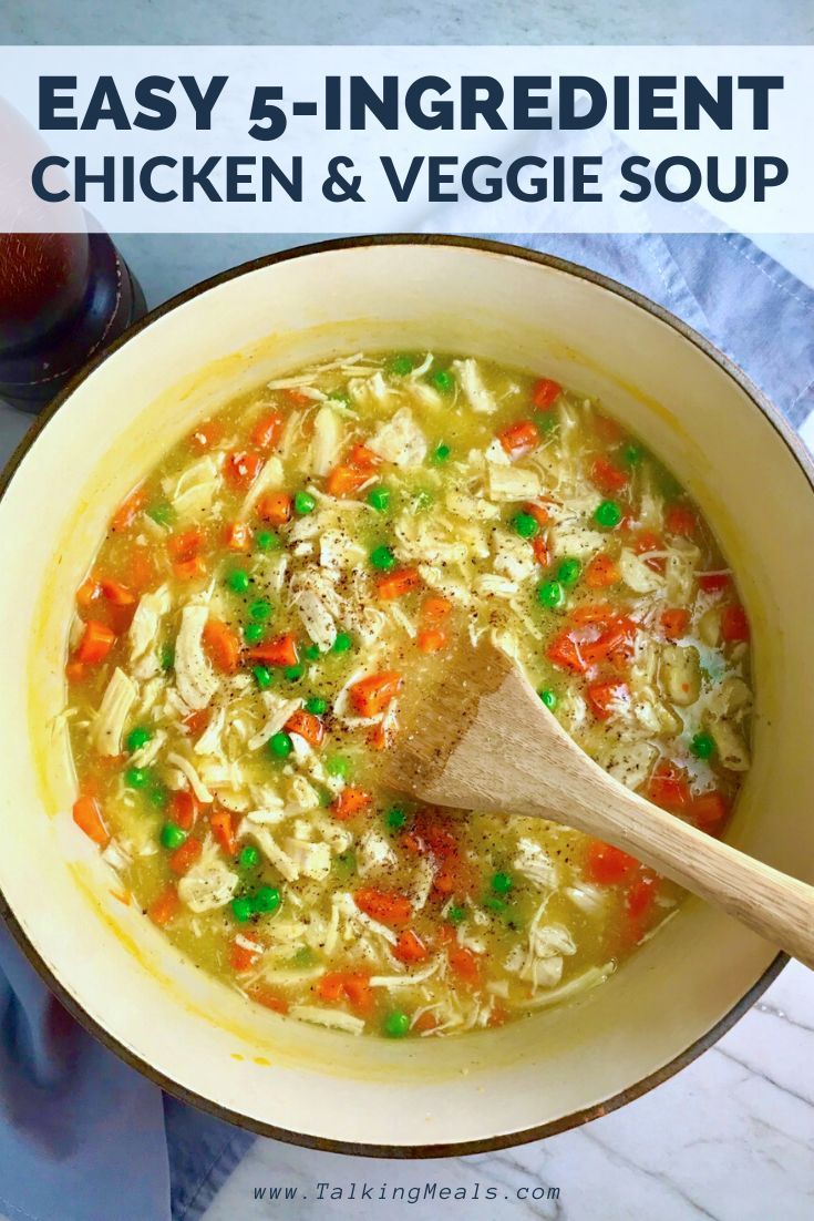 chicken and veggie soup in a white bowl with a wooden spoon on the side