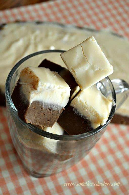 several pieces of chocolate and marshmallow in a glass on a checkered tablecloth