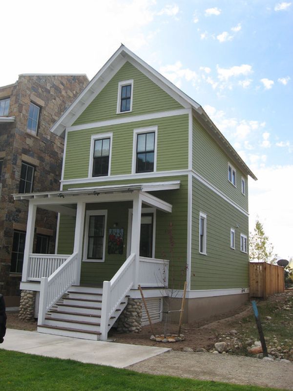 a green two story house with white balconies on the front and second story