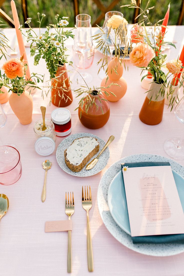 the table is set with plates, silverware and flowers