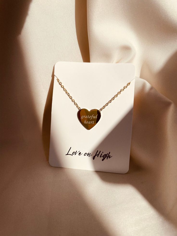 Our Grateful Heart Necklace was meticulously crafted to keep cherished sentiments near and dear, offering a daily reminder of gratitude and faith. Designed to be more than just an accessory, this necklace serves as a tangible connection to what truly matters. Embrace the delicate beauty of this necklace, featuring an elegant charm engraved on one side. Measuring 12mm by 11mm, the charm is suspended from a dainty yet durable chain, providing a subtle accent to any ensemble. Crafted with precision Tarnish Resistant Heart Pendant Necklace For Mother's Day, Tarnish Resistant Heart Necklace For Mother's Day, Gold Minimalist Heart Necklace For Anniversary, Tarnish Resistant Necklaces For Mother's Day Anniversary Gift, Tarnish Resistant Necklaces For Anniversary And Mother's Day, Tarnish Resistant Necklace For Anniversary, Mother's Day, Meaningful Jewelry For Best Friend Gift On Valentine's Day, Elegant Heart Pendant Necklace For Best Friend, Inspirational Gold Necklaces For Valentine's Day