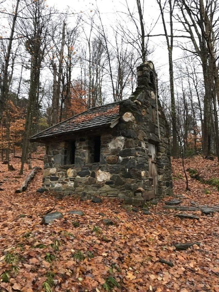 an old stone cabin in the woods surrounded by leaves