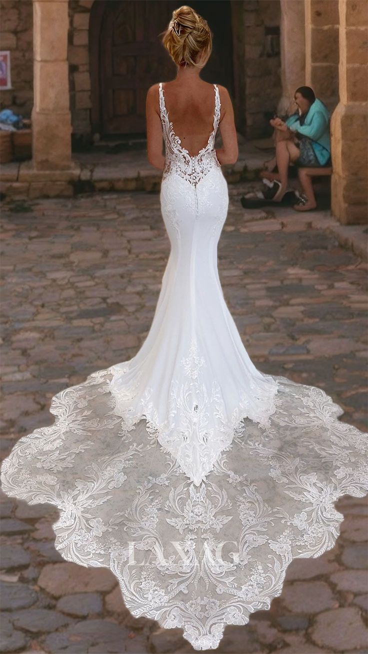 a woman in a white wedding dress standing on a cobblestone street with her back to the camera