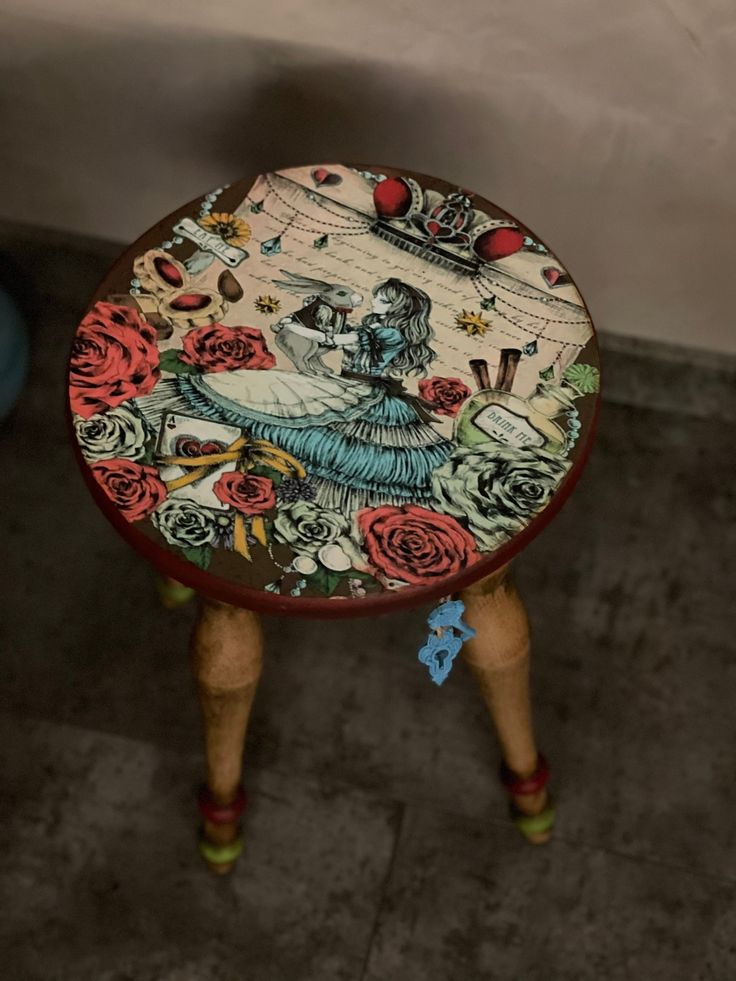 a stool with an image of a woman on it's side and flowers painted on the top