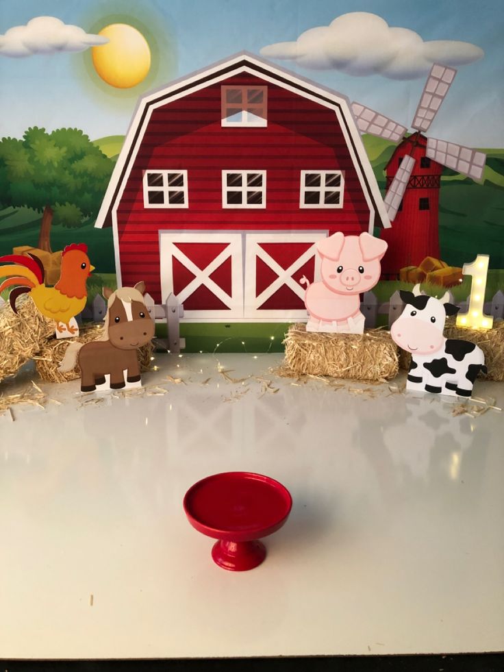 there are farm animals on hay bales in front of a barn and windmills