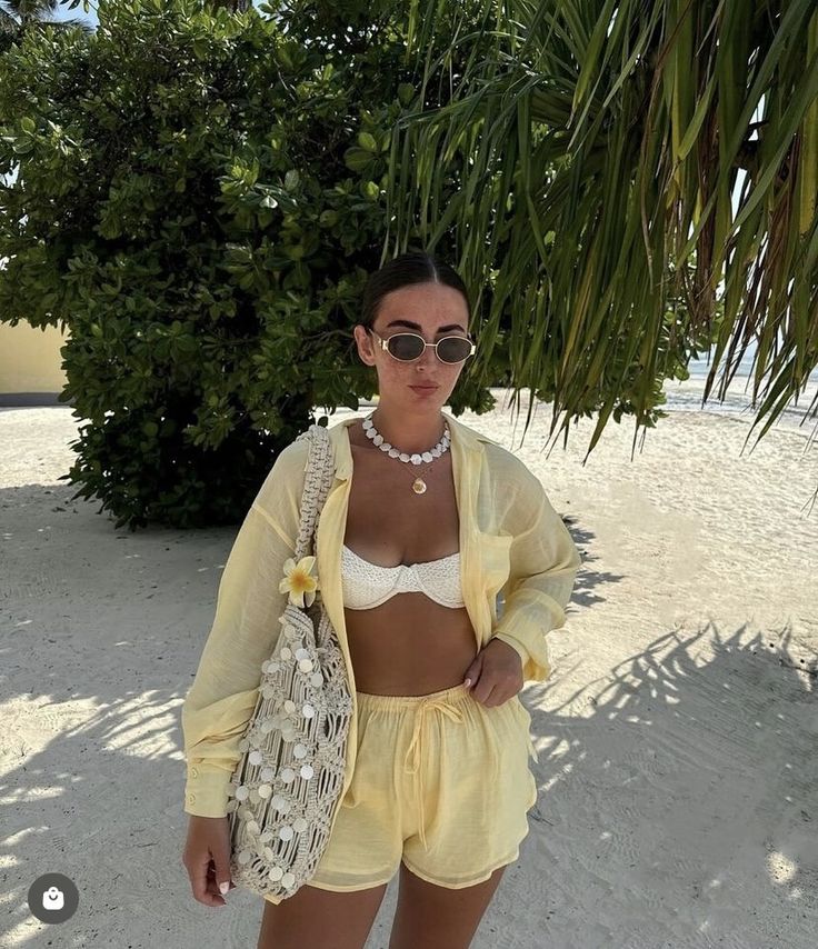 a woman standing on the beach wearing yellow shorts