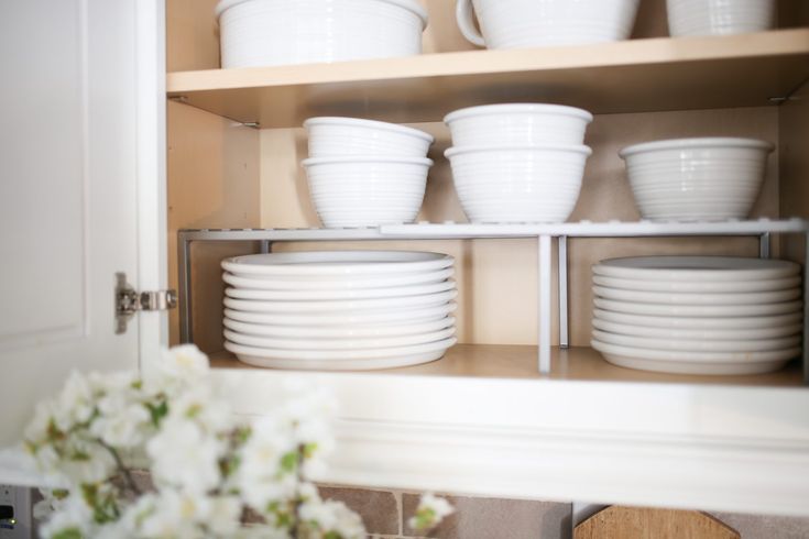 white dishes are stacked on shelves in the kitchen