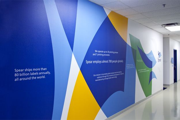 an office hallway with blue, yellow and green graphics on the wall next to it