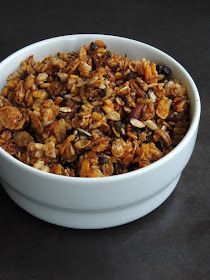 a white bowl filled with granola sitting on top of a black table next to a cup