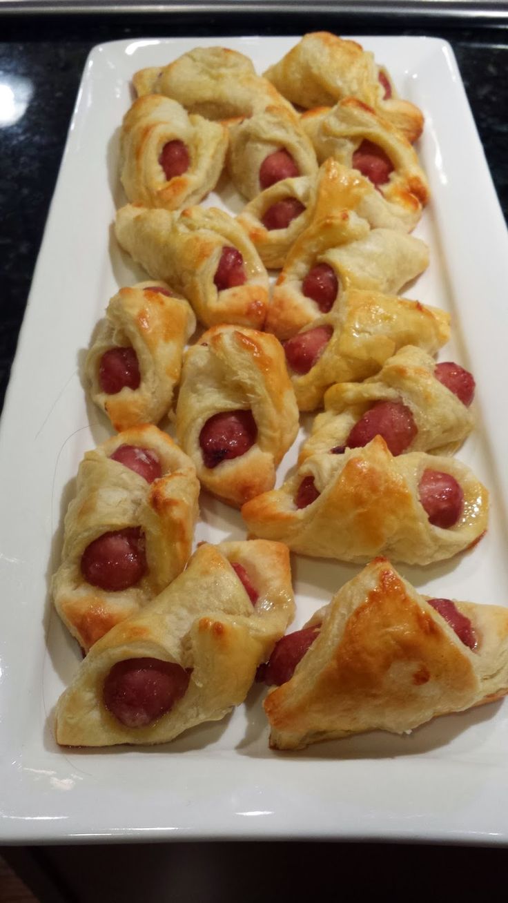 a white plate topped with pigs in a blanket pastries on top of a table