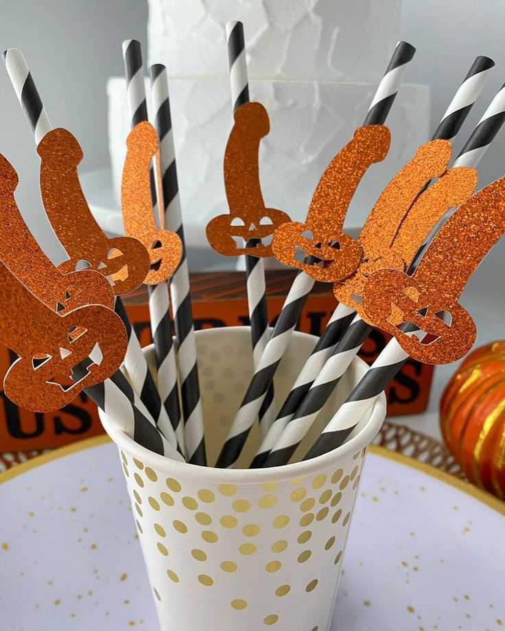 orange and black striped paper straws in a cup with squirrel cutouts on them