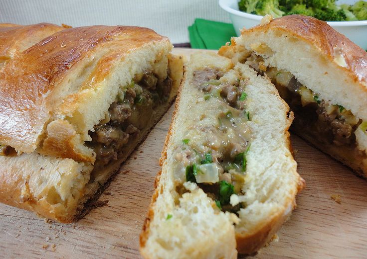 a cut in half sandwich sitting on top of a cutting board next to broccoli