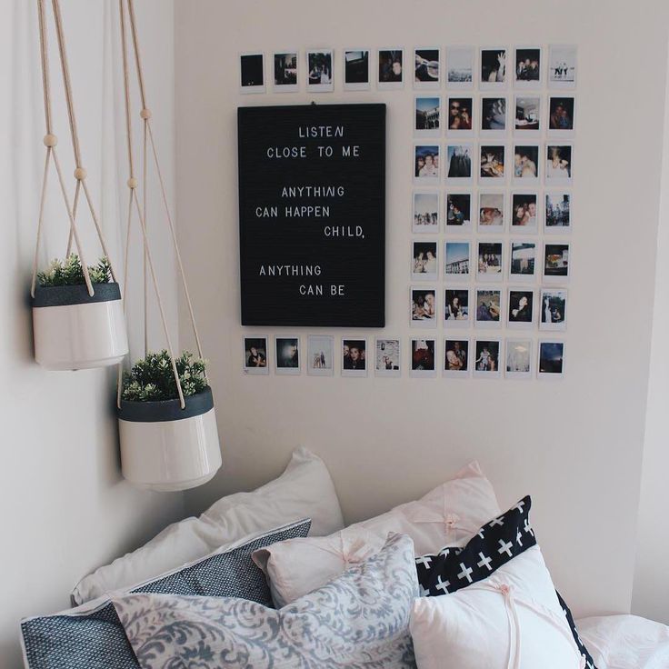 a bed with lots of pillows and pictures on the wall above it, along with hanging planters