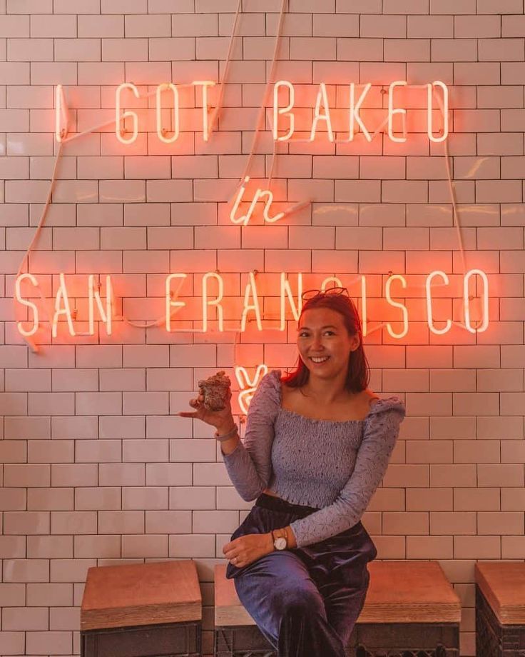 a woman sitting on a bench in front of a neon sign