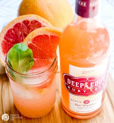 two grapefruits and one orange are on a cutting board next to a drink